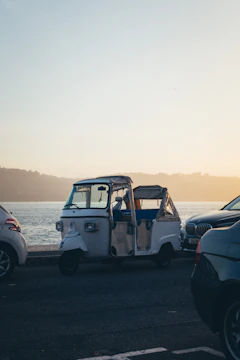 Tuk tuk cruising near the iconic Belém Tower with a glowing sunset backdrop.