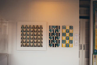 Artistic close-up of modern wall art with gold and neutral tones hanging in a bright, spacious room.