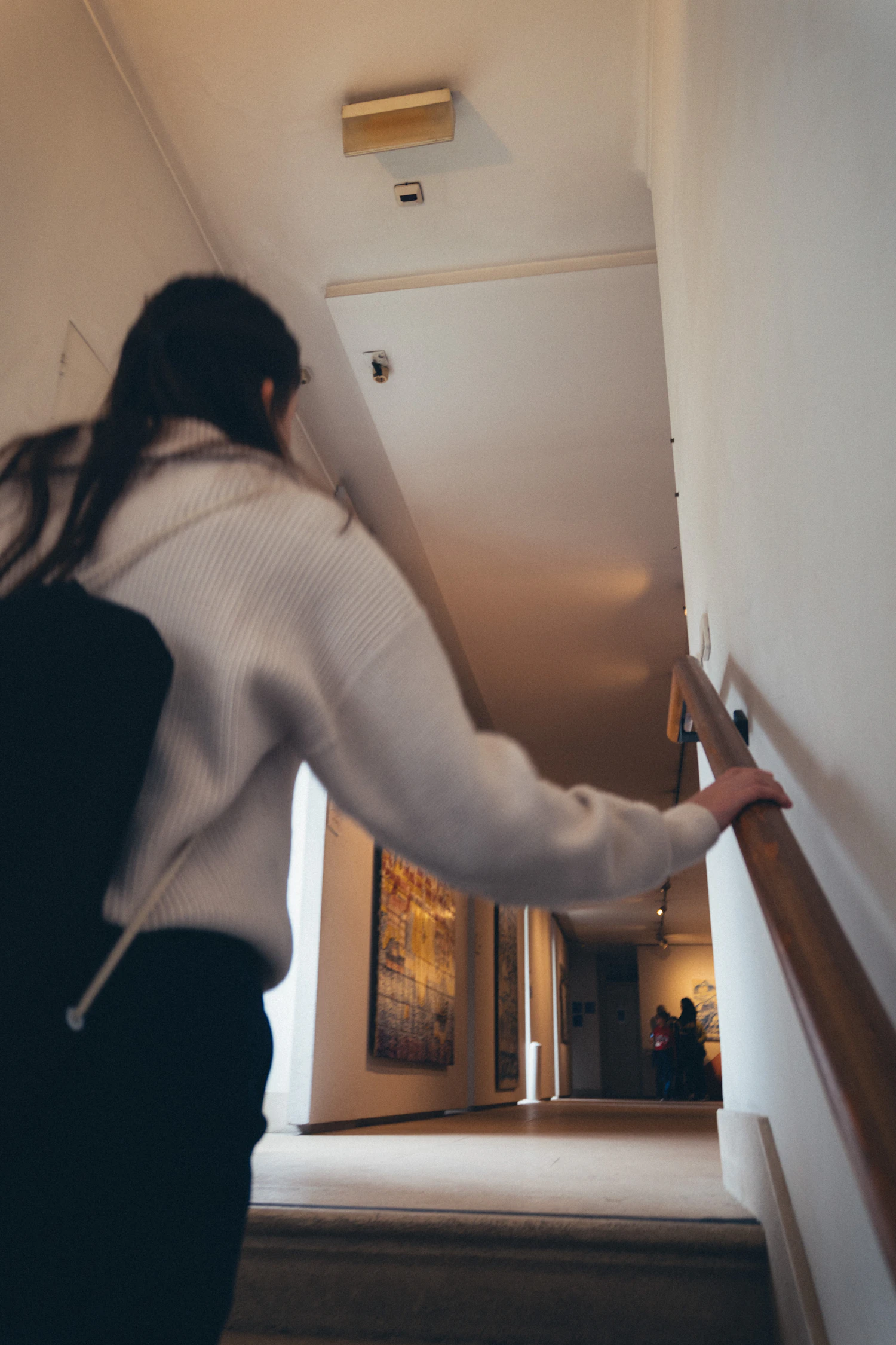 Woman walking up an indoor staircase.
