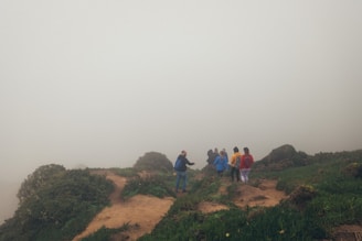 Local guides leading a small group through a misty jungle path.
