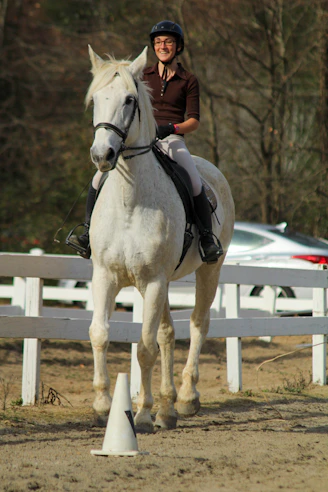 a woman riding on the back of a white horse