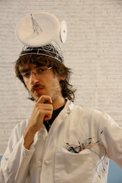 a man in a white lab coat with a hat on his head
