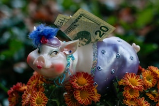 a pig figurine sitting on top of a bunch of flowers