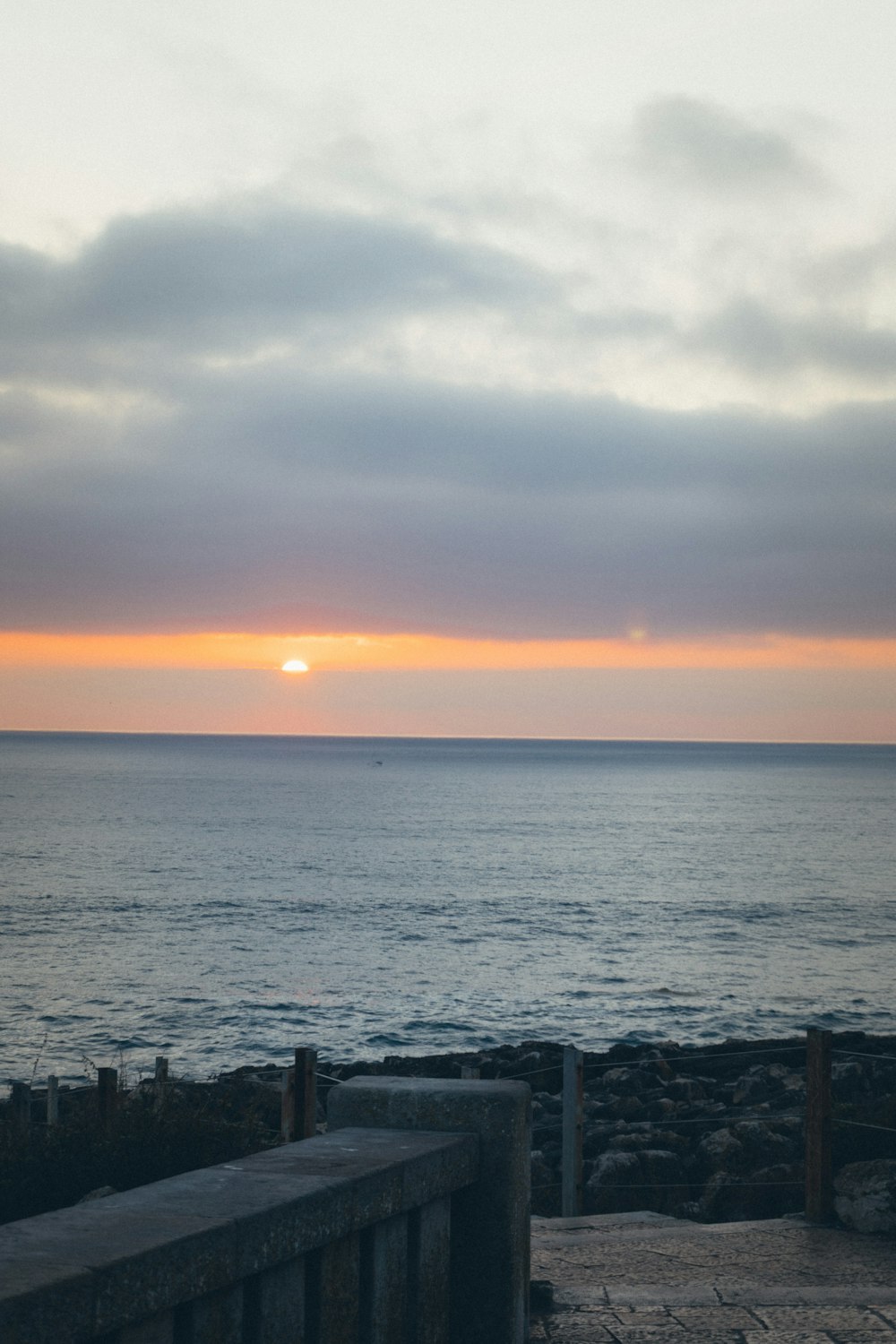 a bench sitting on the side of a beach next to the ocean