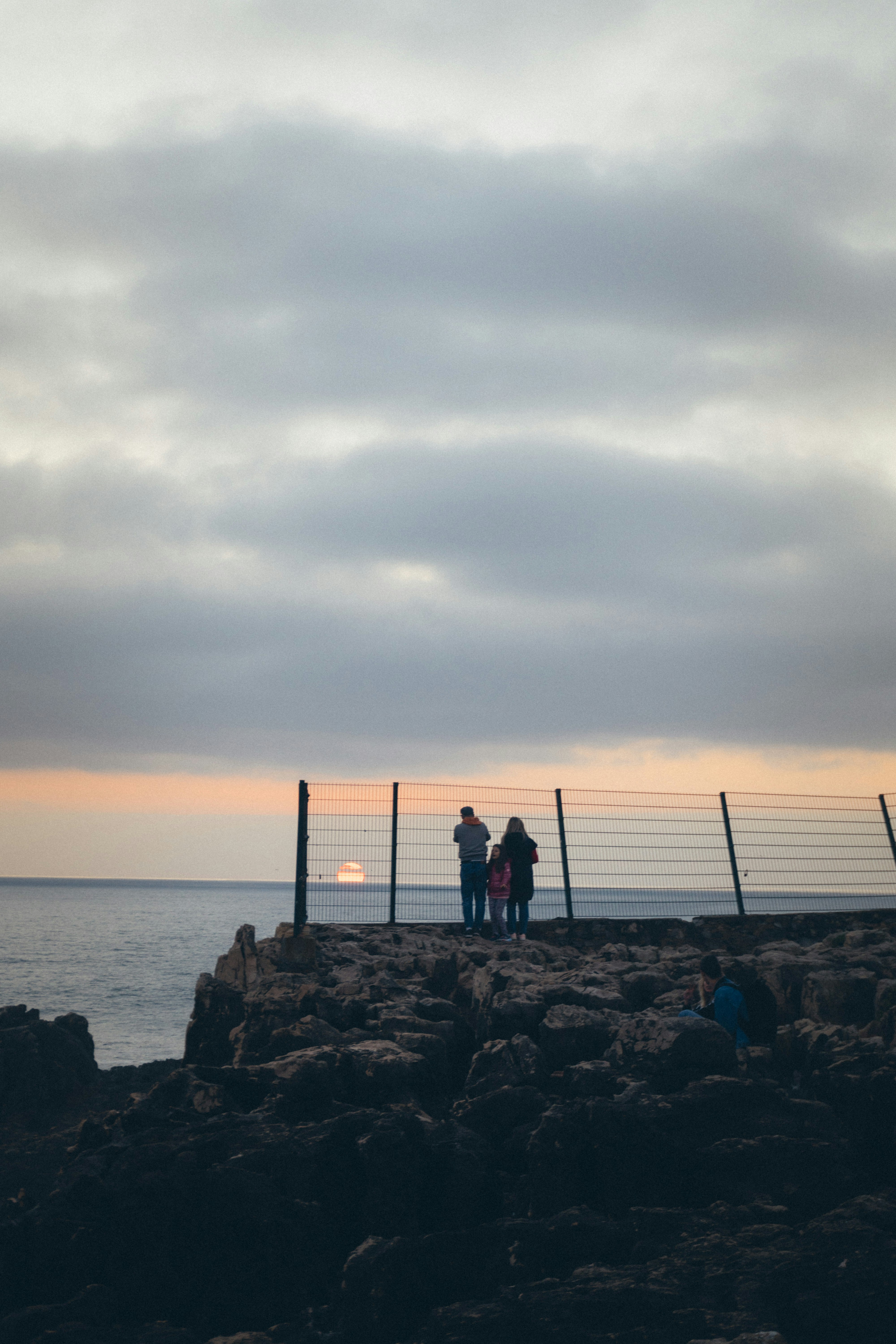 a couple of people standing on top of a rocky beach