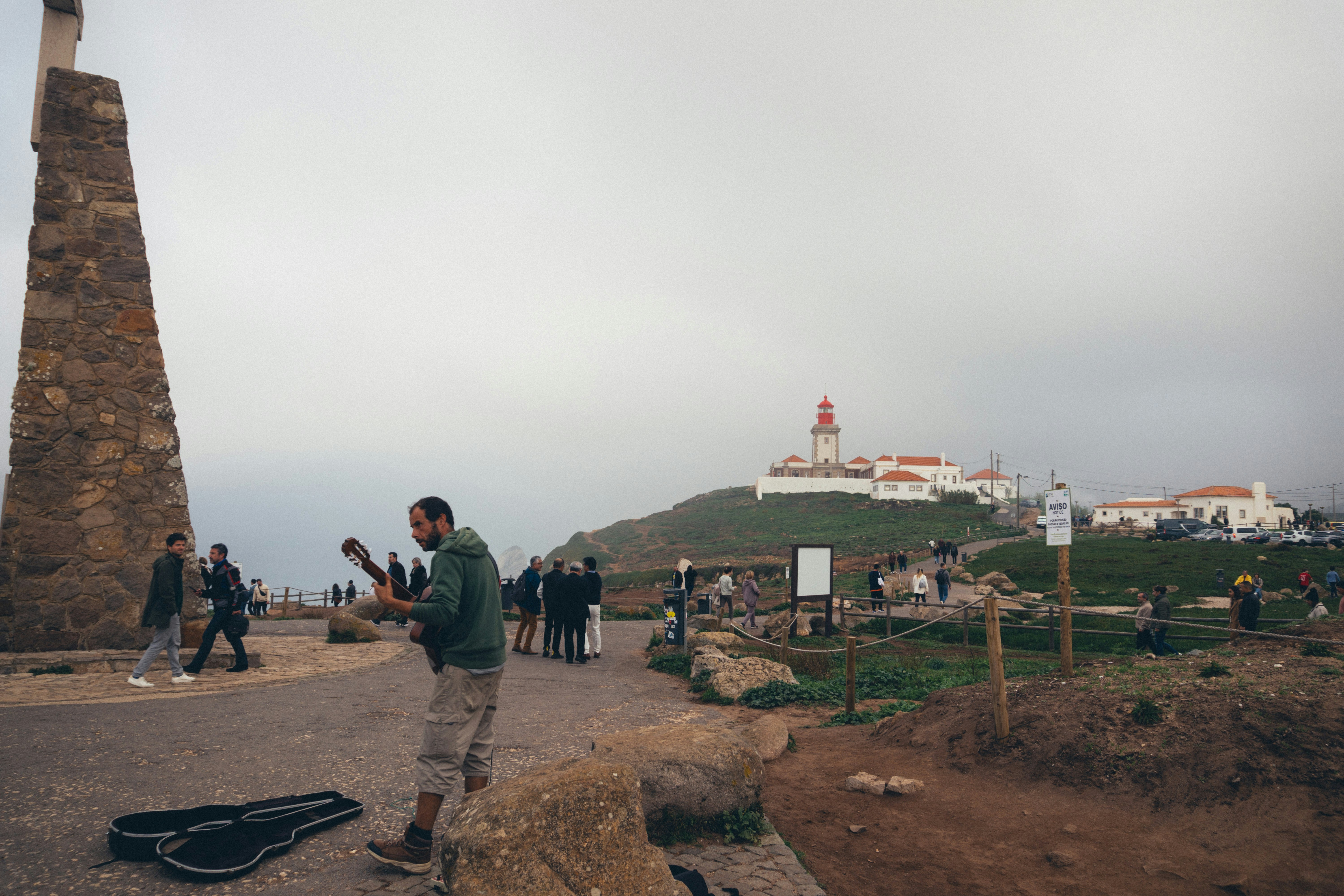 a man standing on top of a hill next to a lighthouse