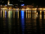 Nighttime shot of a waterfront property with shimmering reflections on the water.