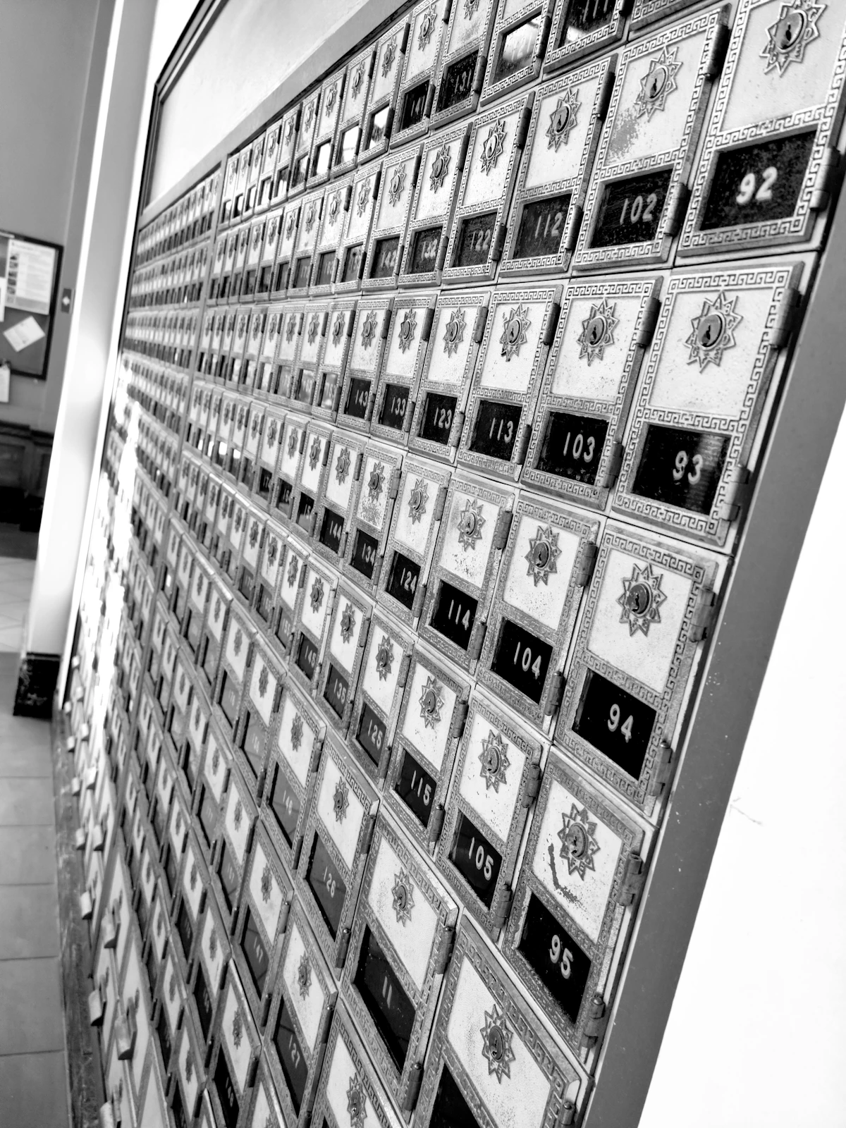 A wall of numbered mailboxes in a building lobby, analogous to a shared mailroom whose delivery speed for a repeated item quietly signals what a neighbor already received