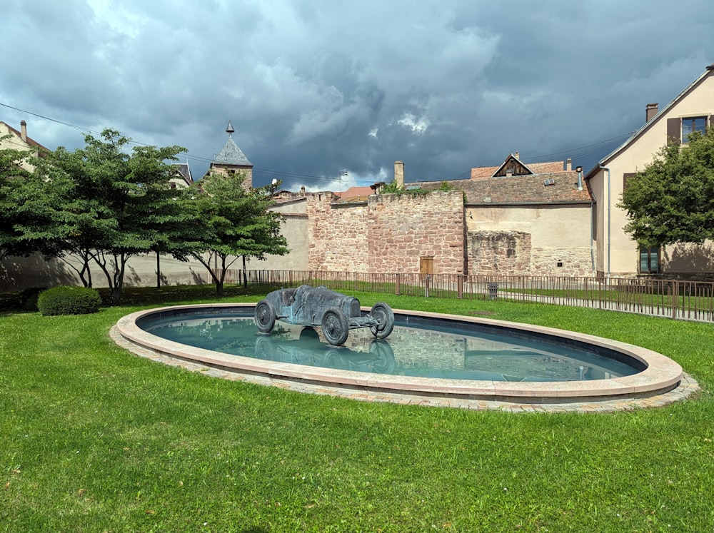 a fountain in a grassy area with a building in the background