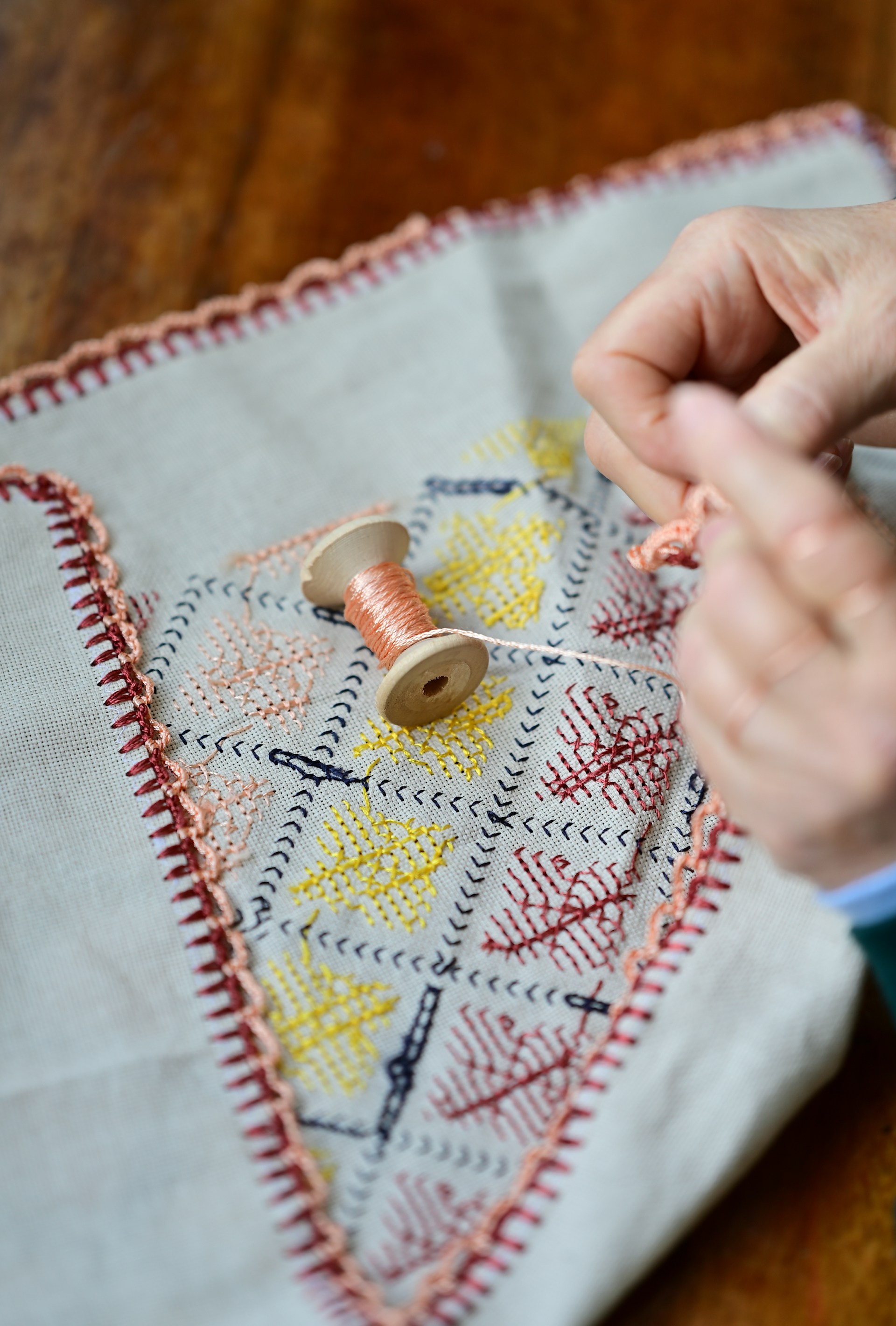 a person is stitching a piece of fabric on a table