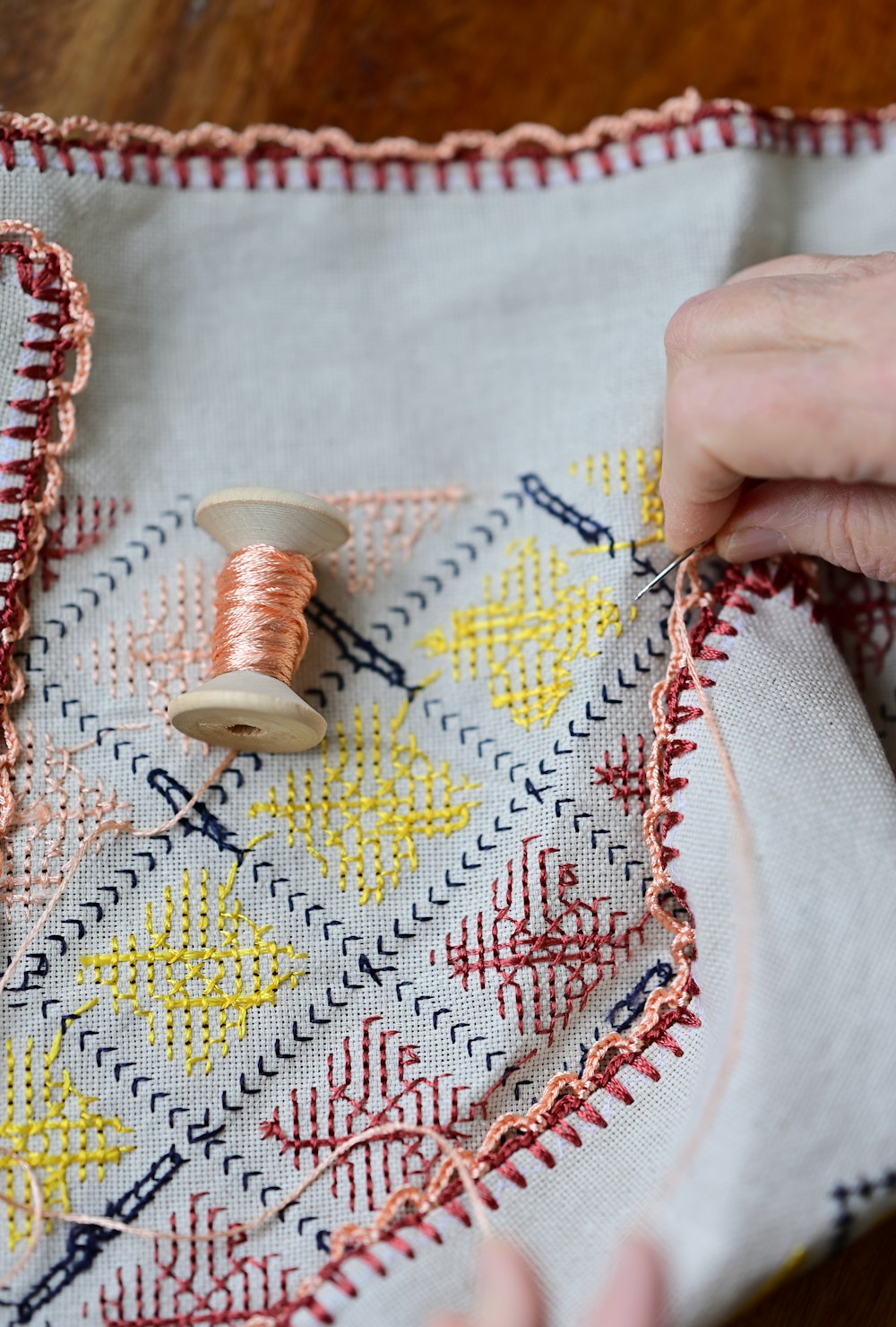 a hand is stitching a piece of fabric with a needle