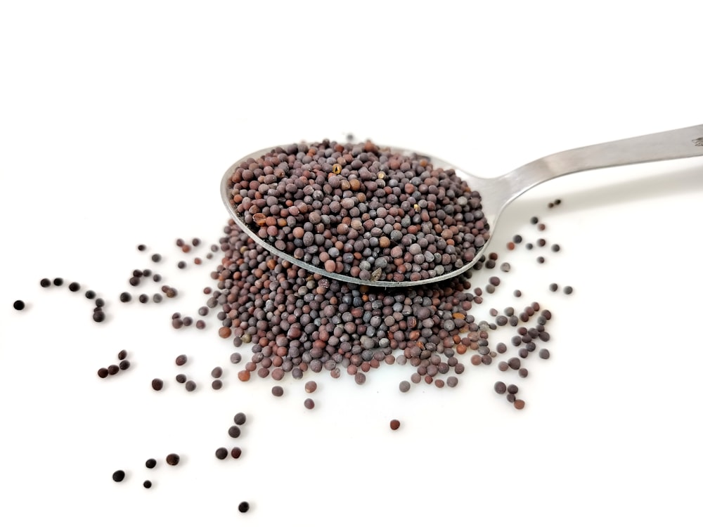 a spoon filled with black seed on top of a white table