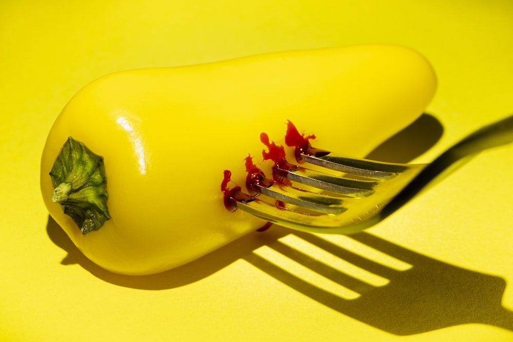 a close up of a fork with a yellow pepper on it