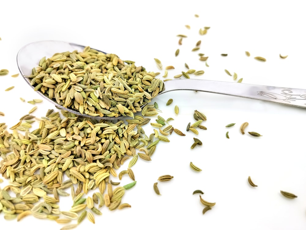 a spoon filled with seeds on top of a white table