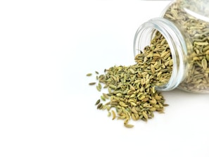 a glass jar filled with seeds on top of a white table