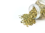 a glass jar filled with seeds on top of a white table