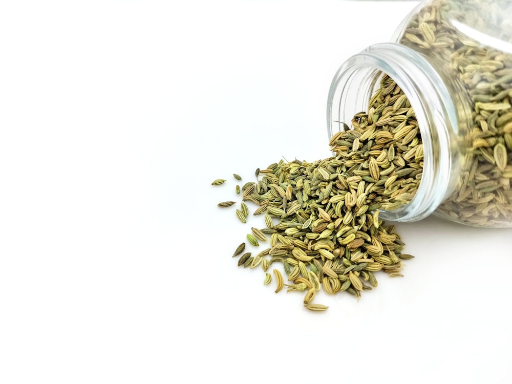 a glass jar filled with seeds on top of a white table