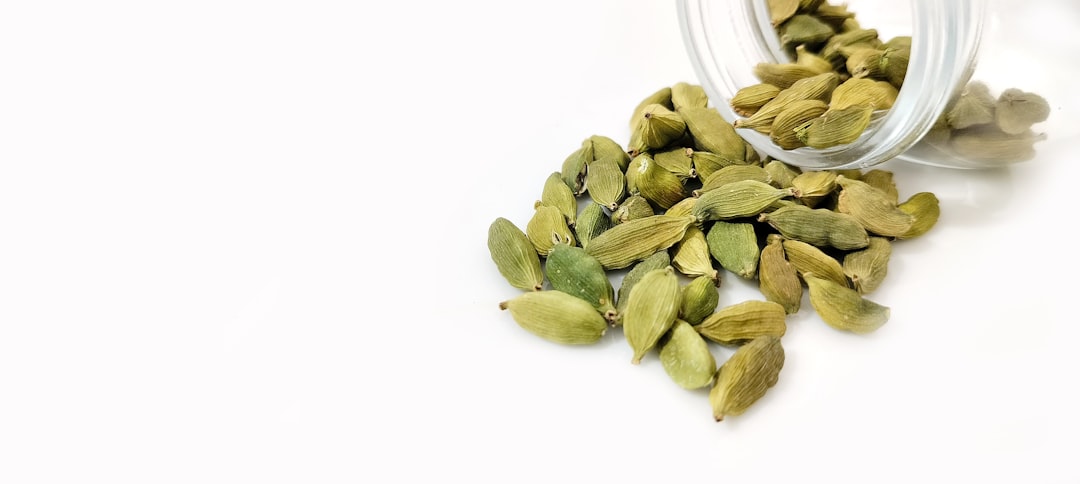 a glass jar filled with nuts on top of a white table, Green Cardamom