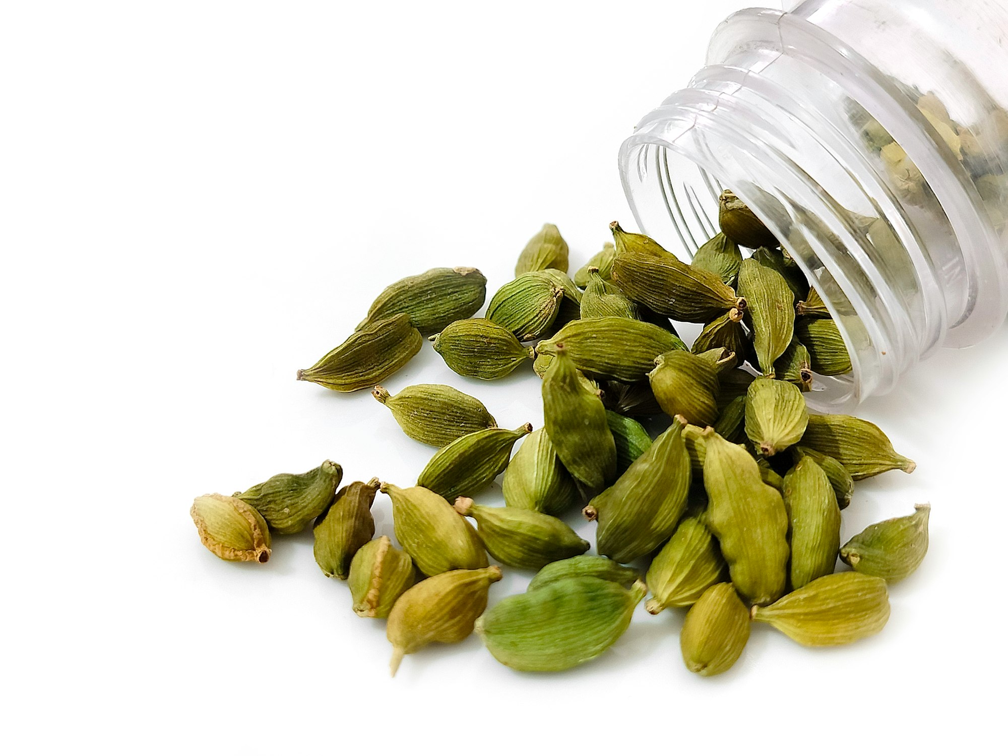 a pile of cardamom seeds next to a bottle of water