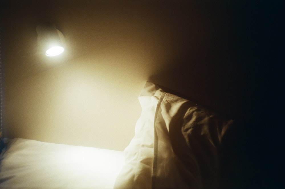 a bed with a white comforter and a light on the wall