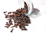 a glass jar filled with cloves on top of a white table