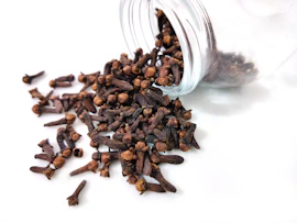 a glass jar filled with cloves on top of a white table