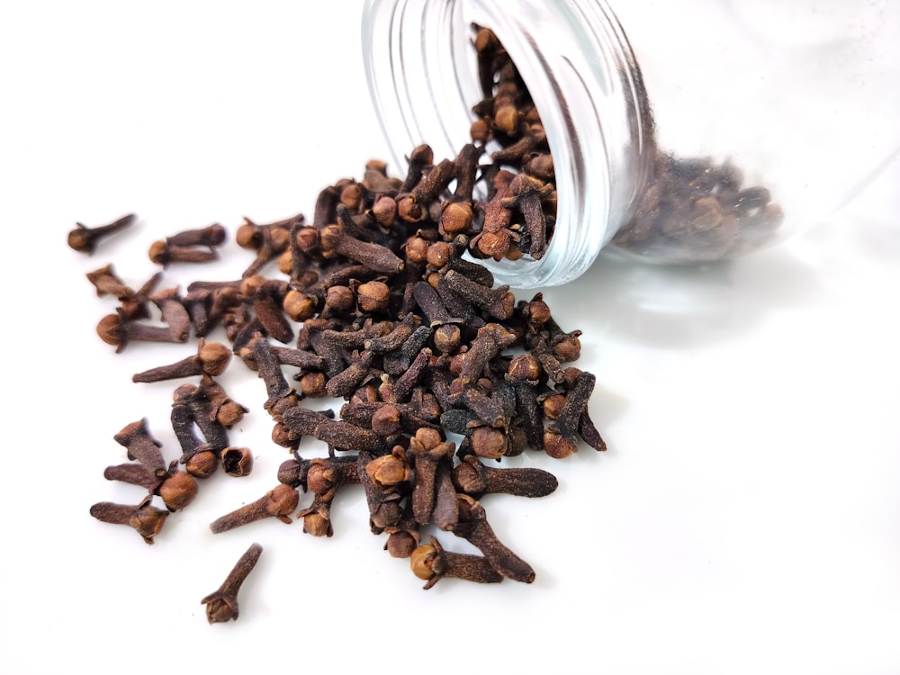 a glass jar filled with cloves on top of a white table