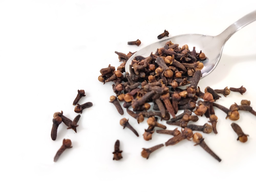 a spoon full of cloves on a white surface