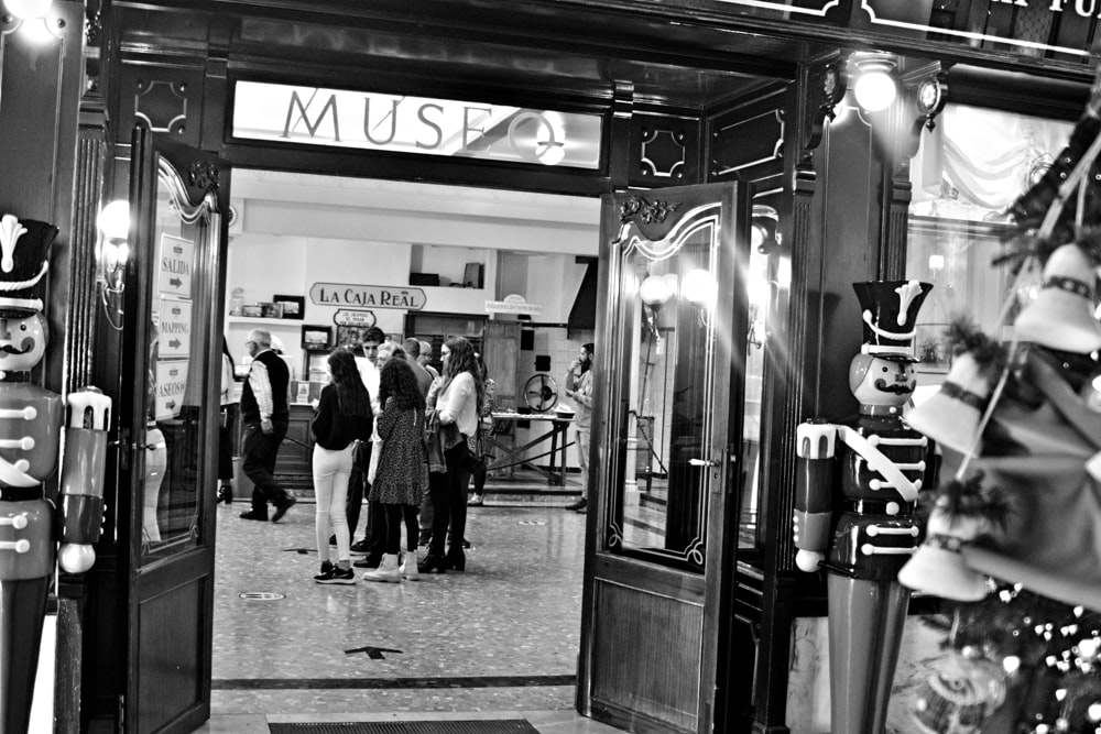 a black and white photo of people walking in front of a music store