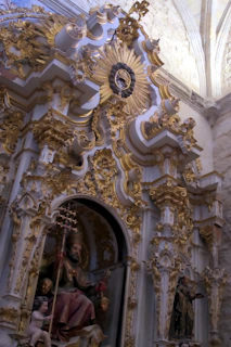 Close-up of an intricately carved black and gold altar with shimmering decorations