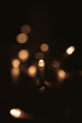 Several small, warm-toned lights are softly glowing against a dark background, creating a cozy and ambient effect. The lights are slightly blurred, enhancing the bokeh effect and giving a dreamy aesthetic.