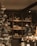 Through a shop window, shelves are filled with a variety of wine bottles, categorized by country labels such as Italy and France. A decorated Christmas tree is visible on the left, adding a festive atmosphere. The lighting is warm and ambient.