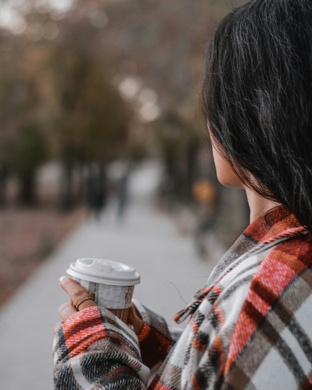 a woman holding a cup of coffee on a sidewalk
