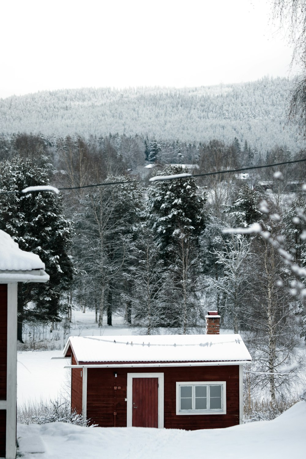 a small red cabin in the middle of a snowy field