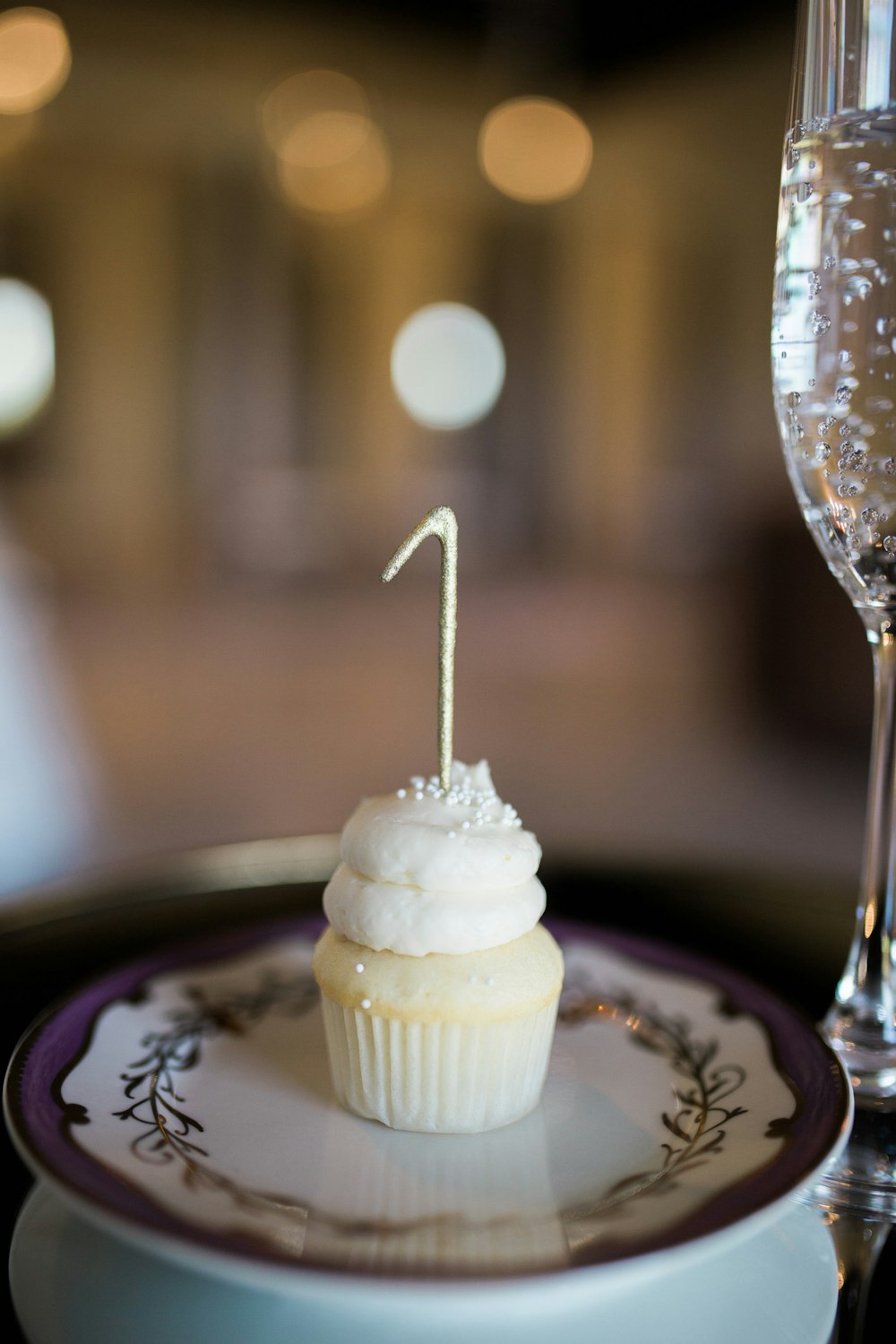 a cupcake on a plate with a candle sticking out of it