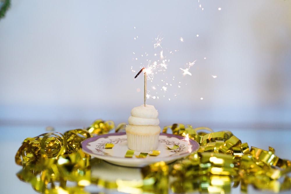 a white cupcake with a sparkler on top of it