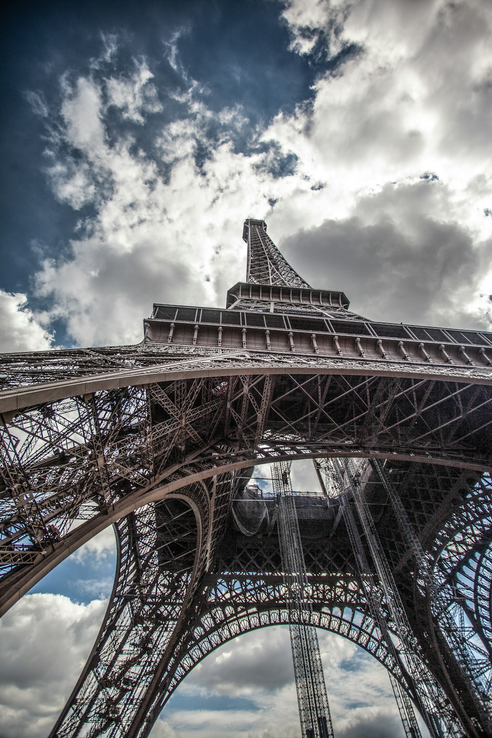 the top of the eiffel tower against a cloudy sky