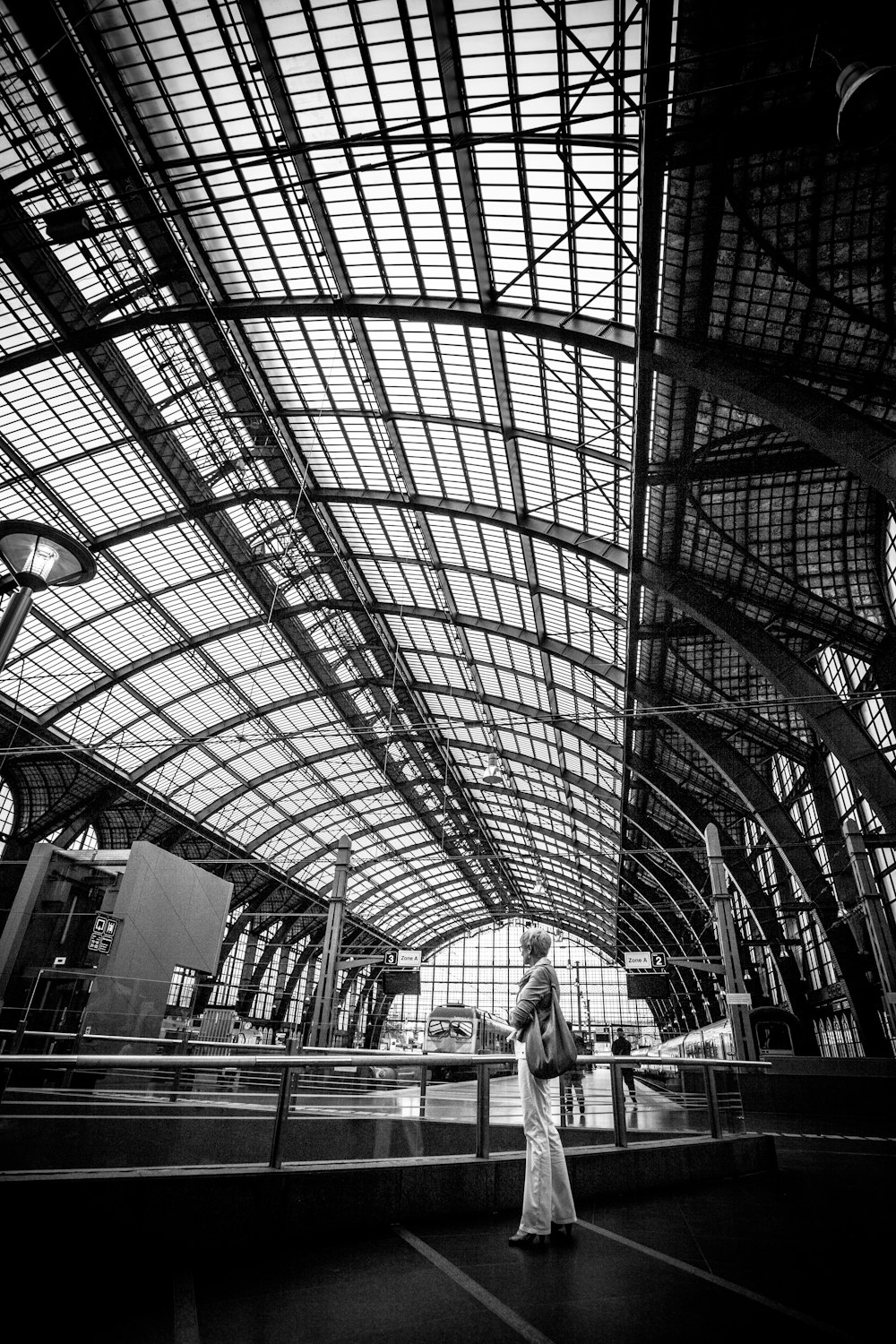 a black and white photo of a woman in a train station