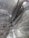 An expansive underground marble quarry features towering, textured marble walls with distinct swirling patterns and light fixtures mounted on them. Wooden ladders and platforms are scattered along the walls, indicating human activity and access.