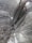 An expansive underground marble quarry features towering, textured marble walls with distinct swirling patterns and light fixtures mounted on them. Wooden ladders and platforms are scattered along the walls, indicating human activity and access.