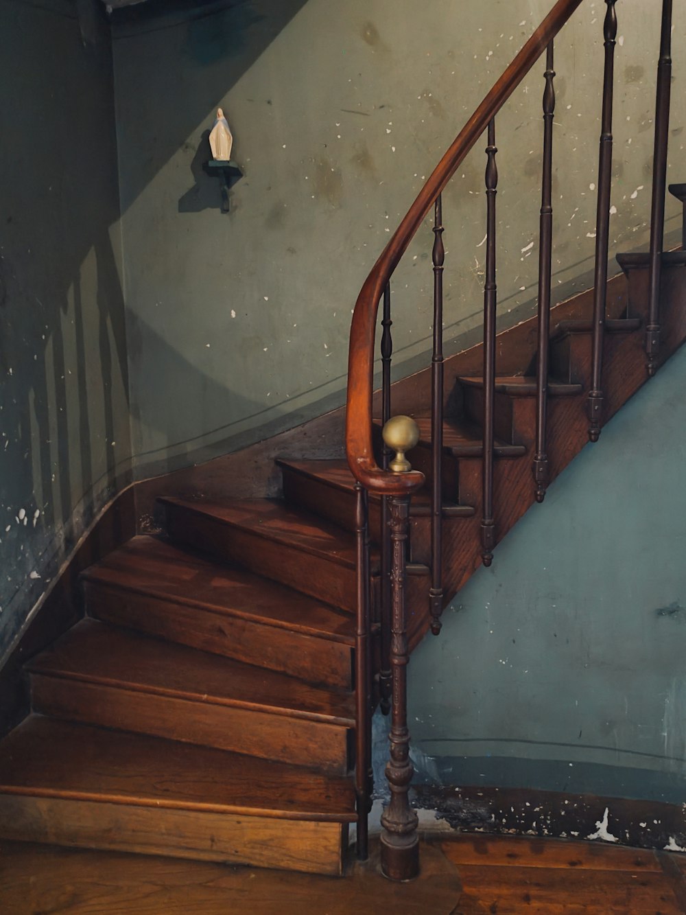 a wooden stair case next to a blue wall