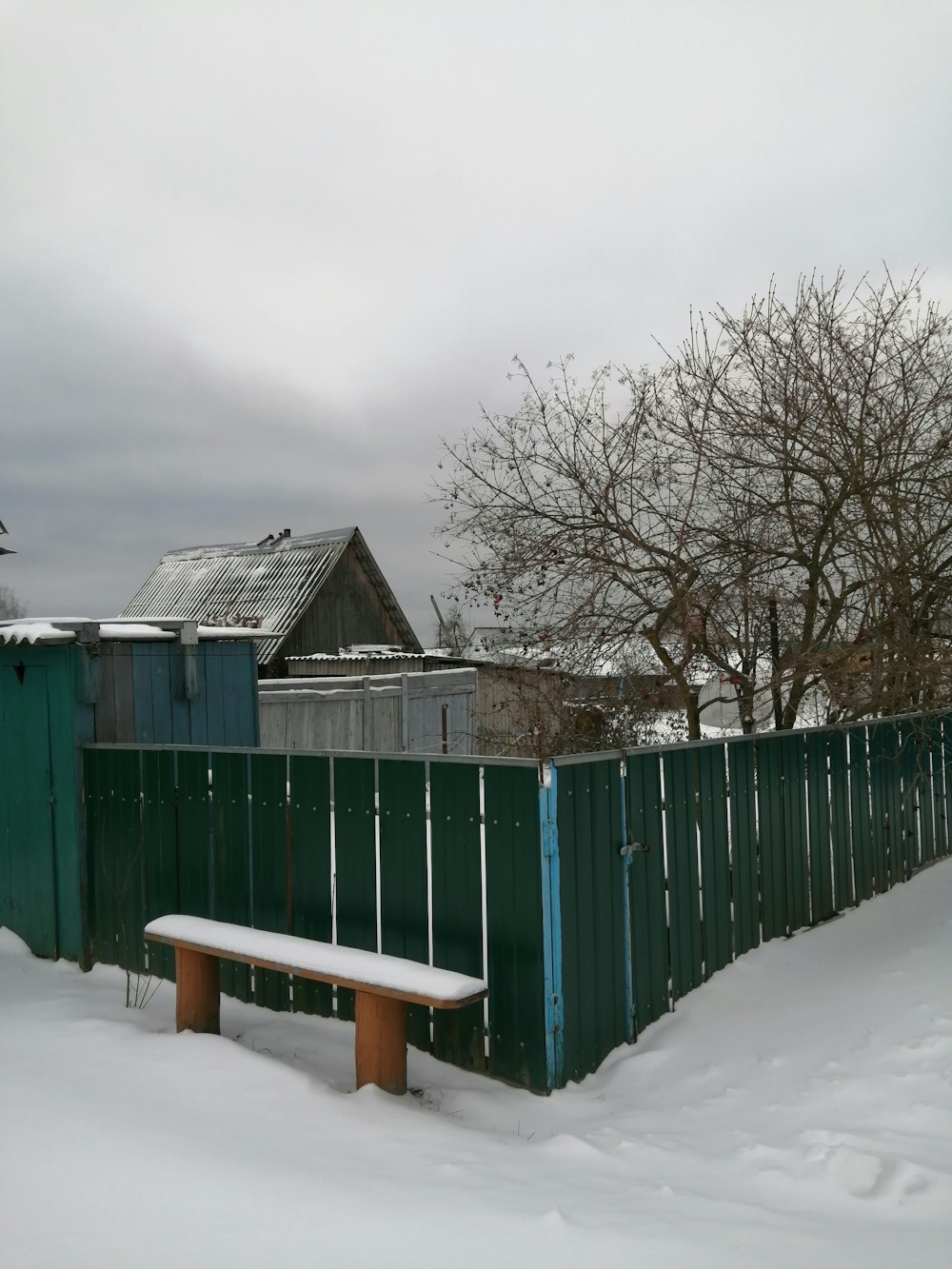eine schneebedeckte Parkbank neben einem Zaun
