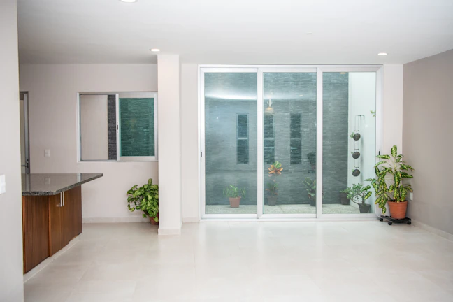 A sleek, modern garden room with large glass doors opening to a lush green backyard.