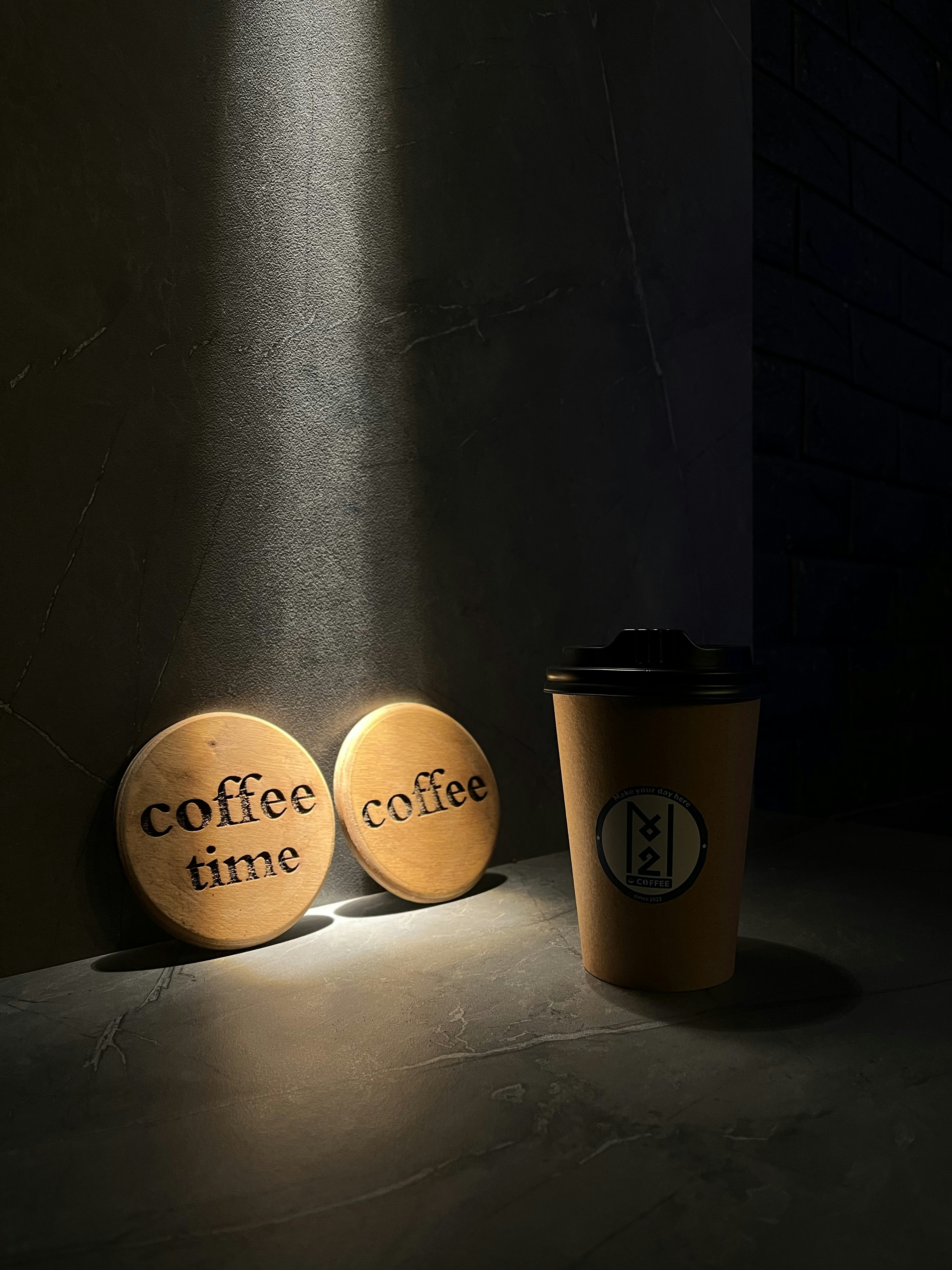 a coffee cup sitting next to two wooden coasters
