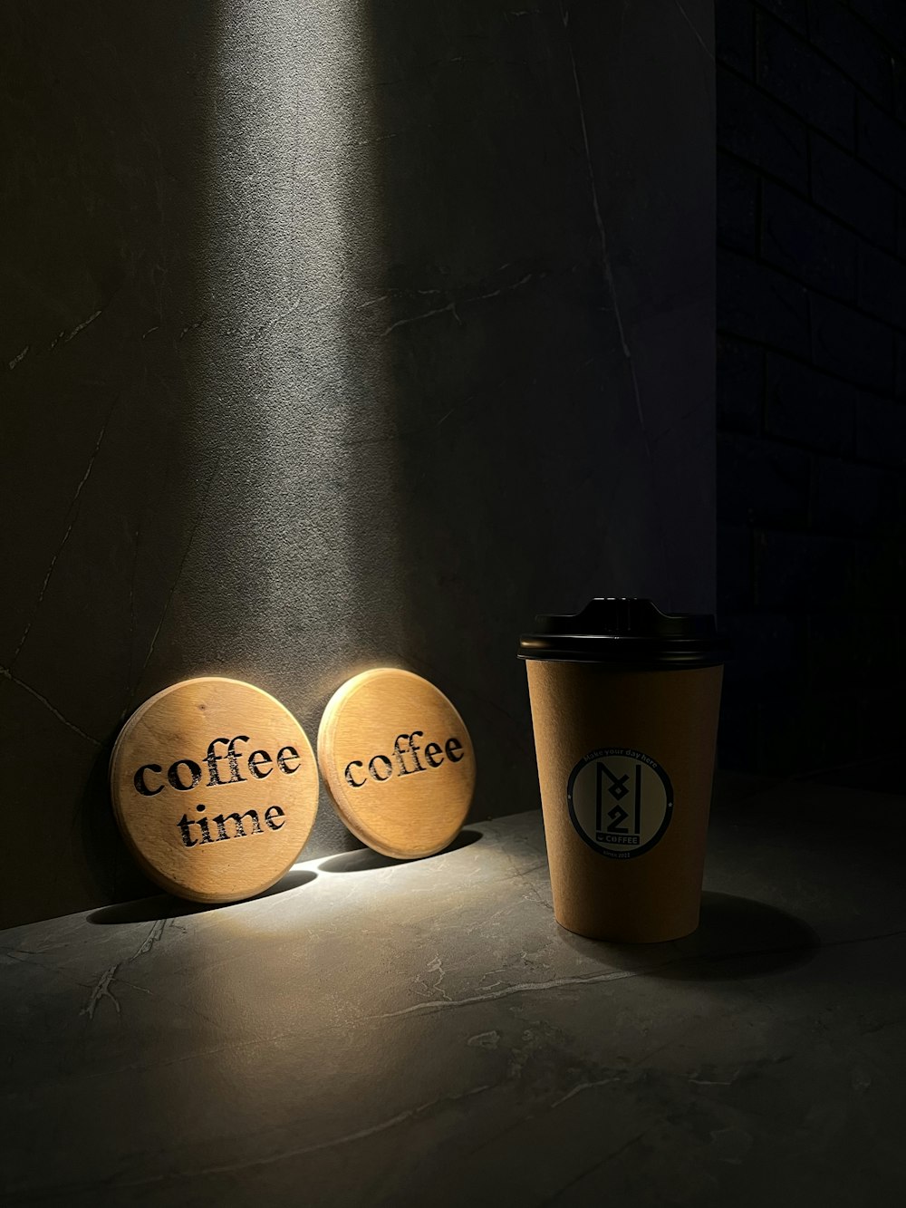 a coffee cup sitting next to two wooden coasters