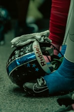 Close-up of a Broncos helmet resting on the field under bright stadium lights.
