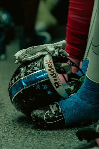 Close-up of a sleek Vipers Fastpitch helmet resting on a wooden bench under stadium lights.