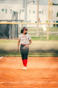 a woman in a baseball uniform standing on a baseball field