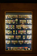 A neatly arranged display of framed certificates and badges on a wooden desk.