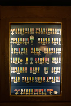 A neatly arranged display of framed certificates and badges on a wooden desk.